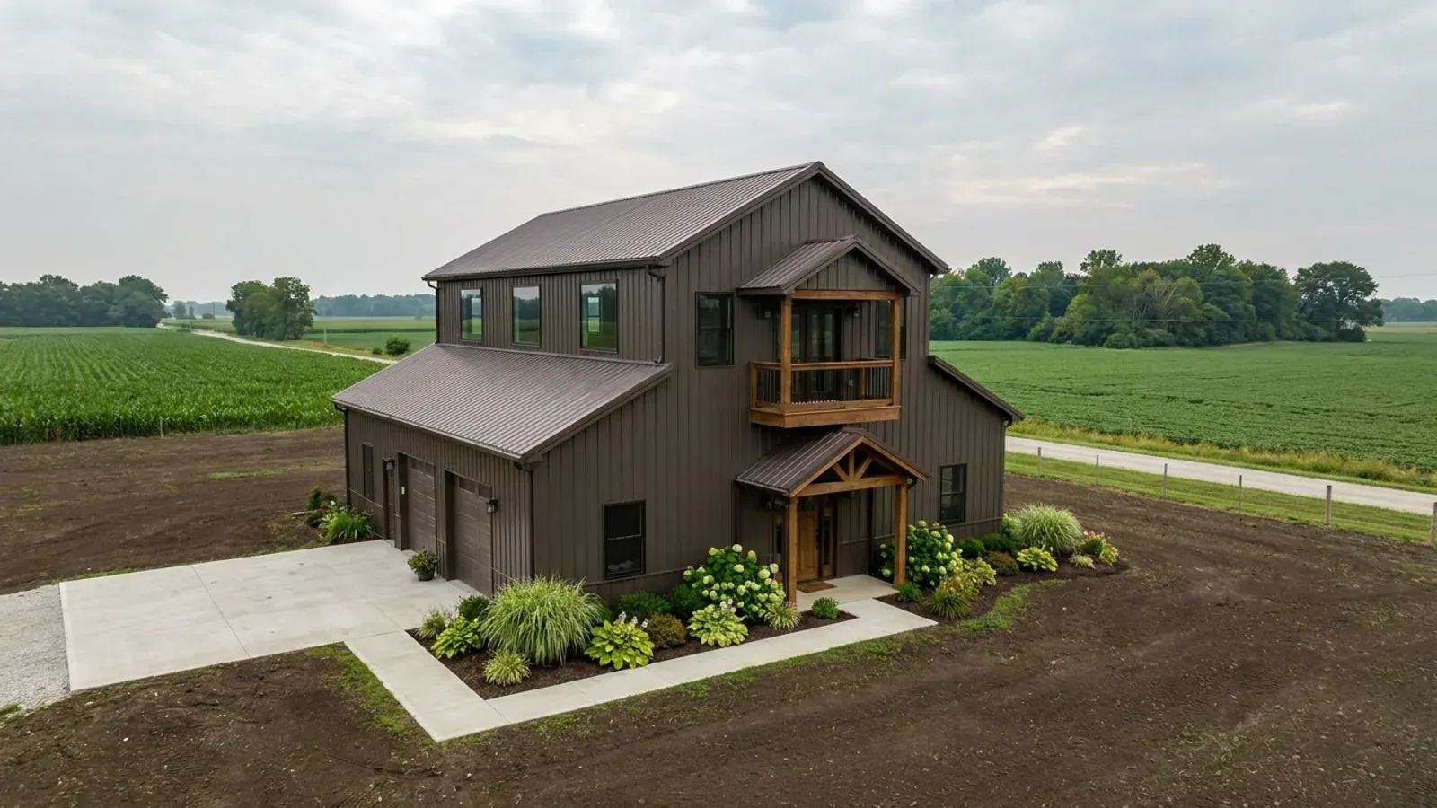 A completed two-story barndominium with visible second-story windows and a small covered balcony above the entry porch.